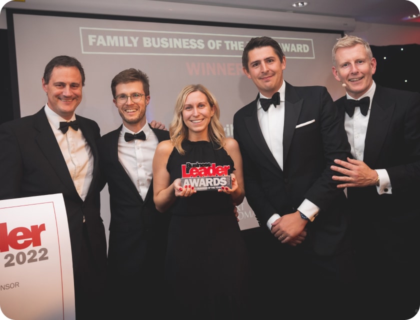 A photo of Tom, Claire and Rich at the Business Leader Awards in 2022, with Claire holding the award trophy and smiling.