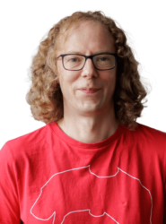 A photo of Mark, who has long brown curly hair and is wearing glasses with a bright red top.