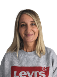 Jane has blonde shoulder length hair and is wearing a grey jumper with the red levis logo on the front of it. She is smiling at the camera.