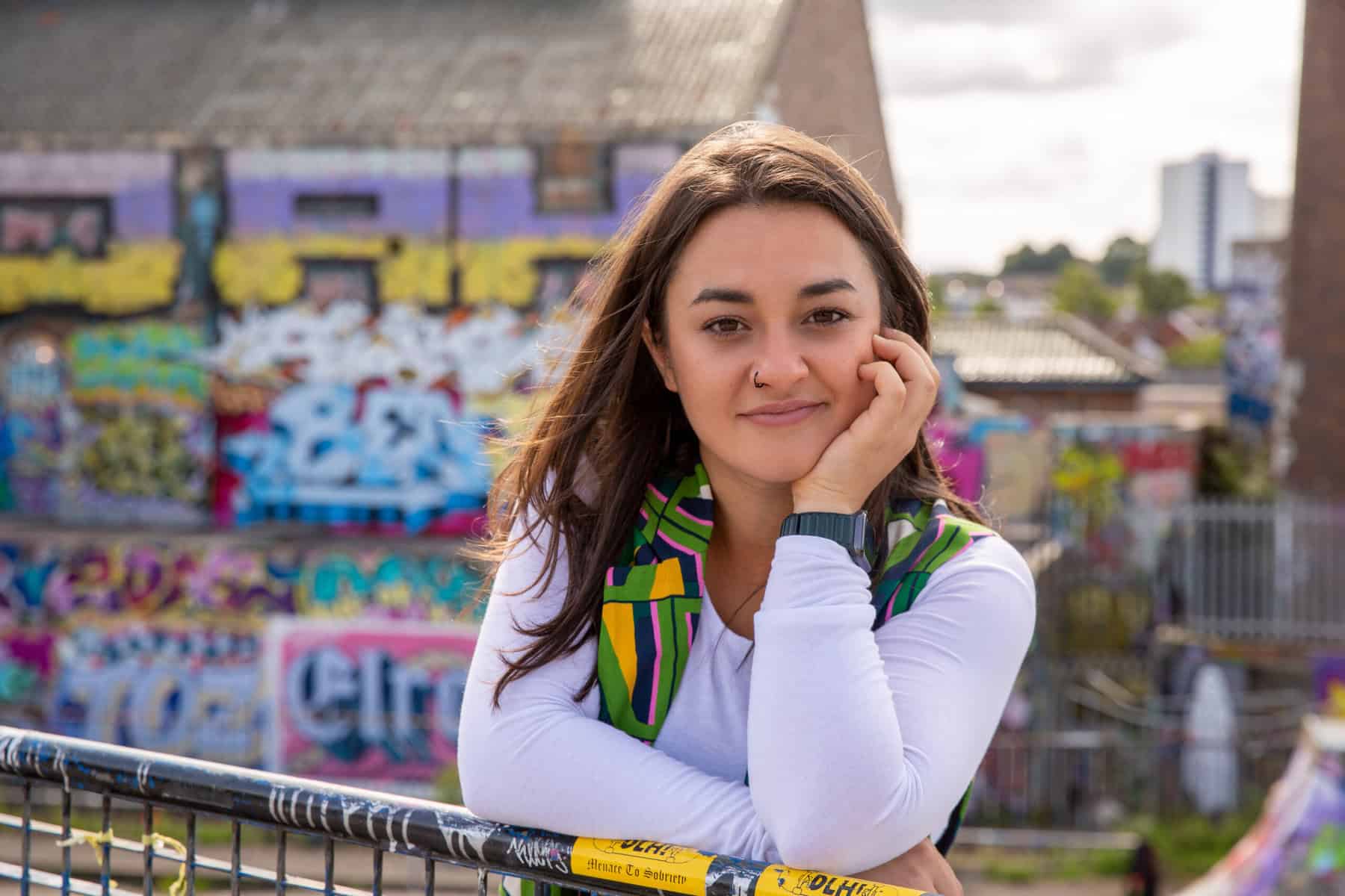 Devon Lowndes, guest speaker for March Skill Sessions, leaning casually on a metal fence in an urban area