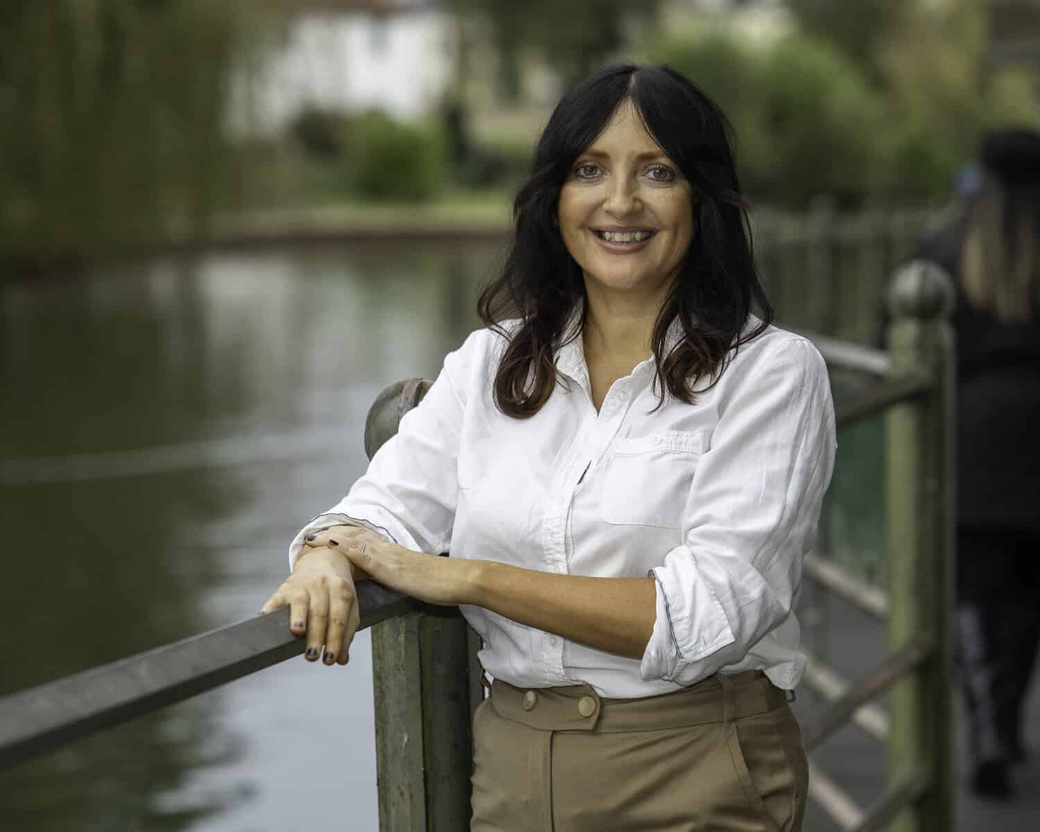 Donna Stevenson, guest speaker for the April Skill Sessions, leaning casually on a metal fence overlooking a large body of water