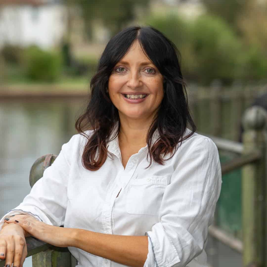 Donna Stevenson, guest speaker for the April Skill Sessions, leaning casually on a metal fence overlooking a large body of water