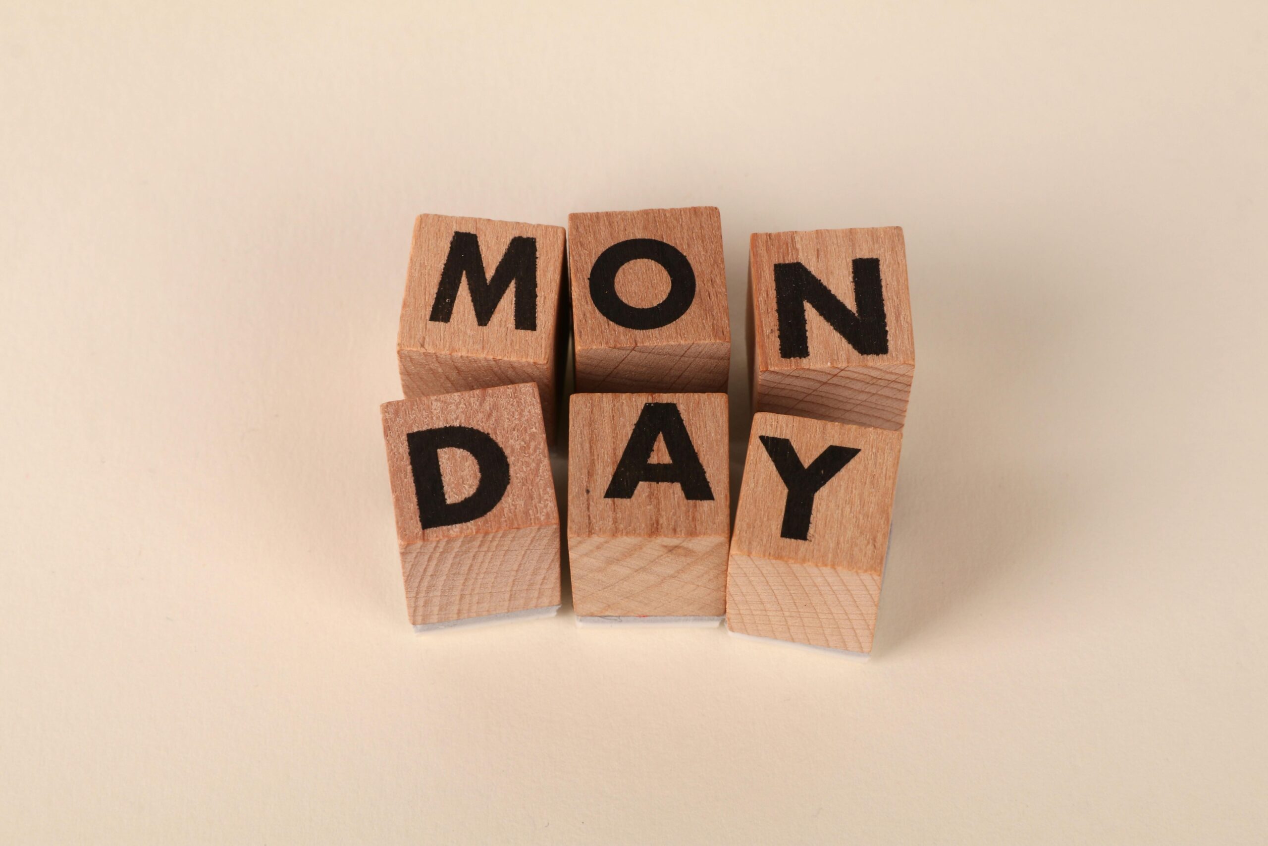Wooden blocks arranged on a light background spell out the word MONDAY in bold black letters, with each letter on a separate block—capturing the start of the working week and the feeling of Sunday Scaries.